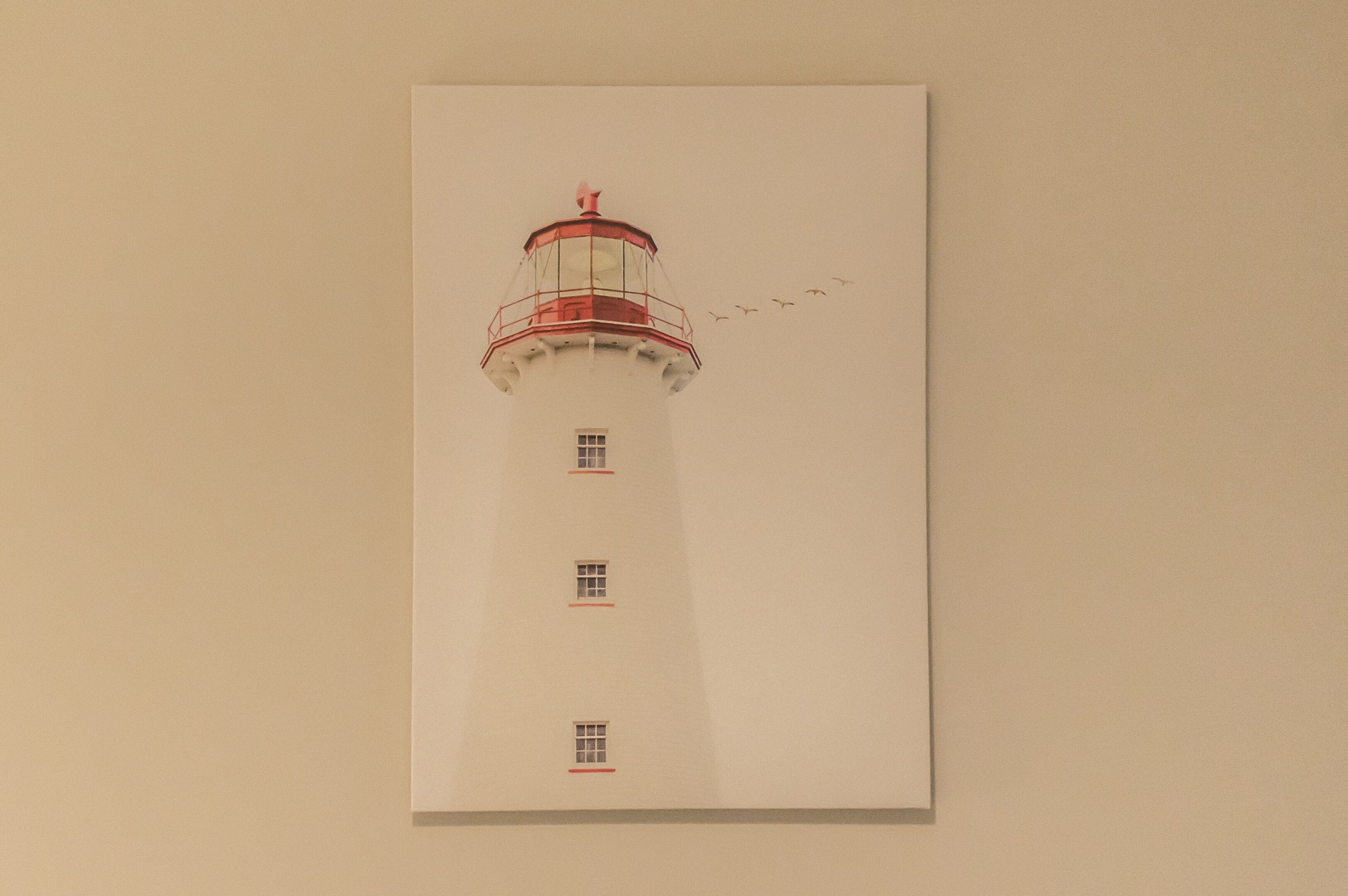Ein Leuchtturm mit roter Spitze und drei Fenstern.