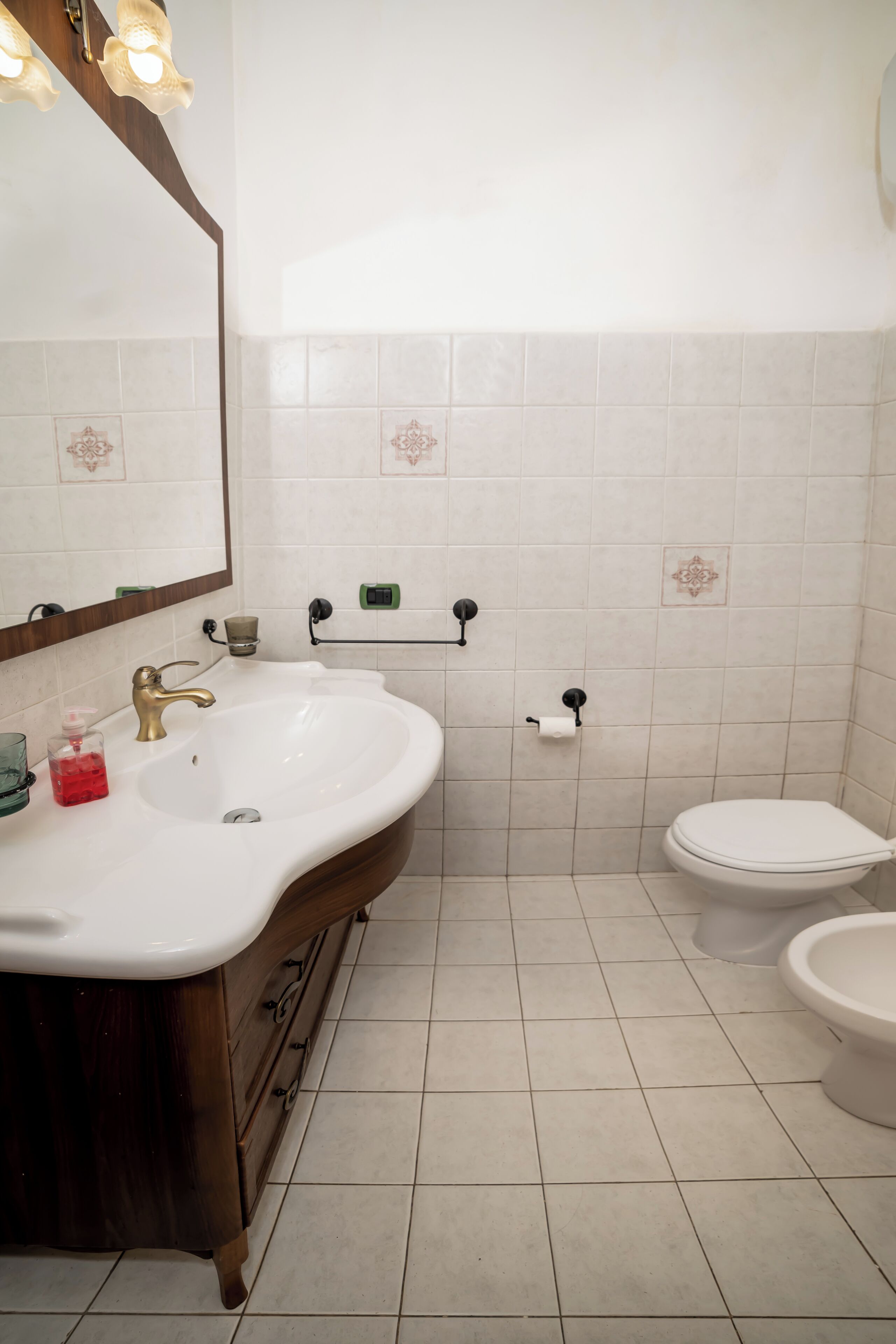 A bathroom with a white sink, a mirror, a toilet, and a towel rack.