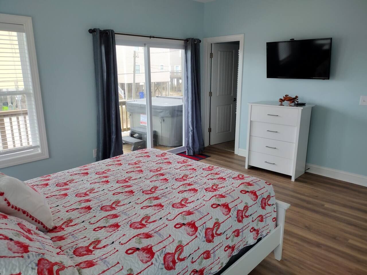 A bedroom with a bed, a dresser, a television, and a sliding door leading to an outdoor area.