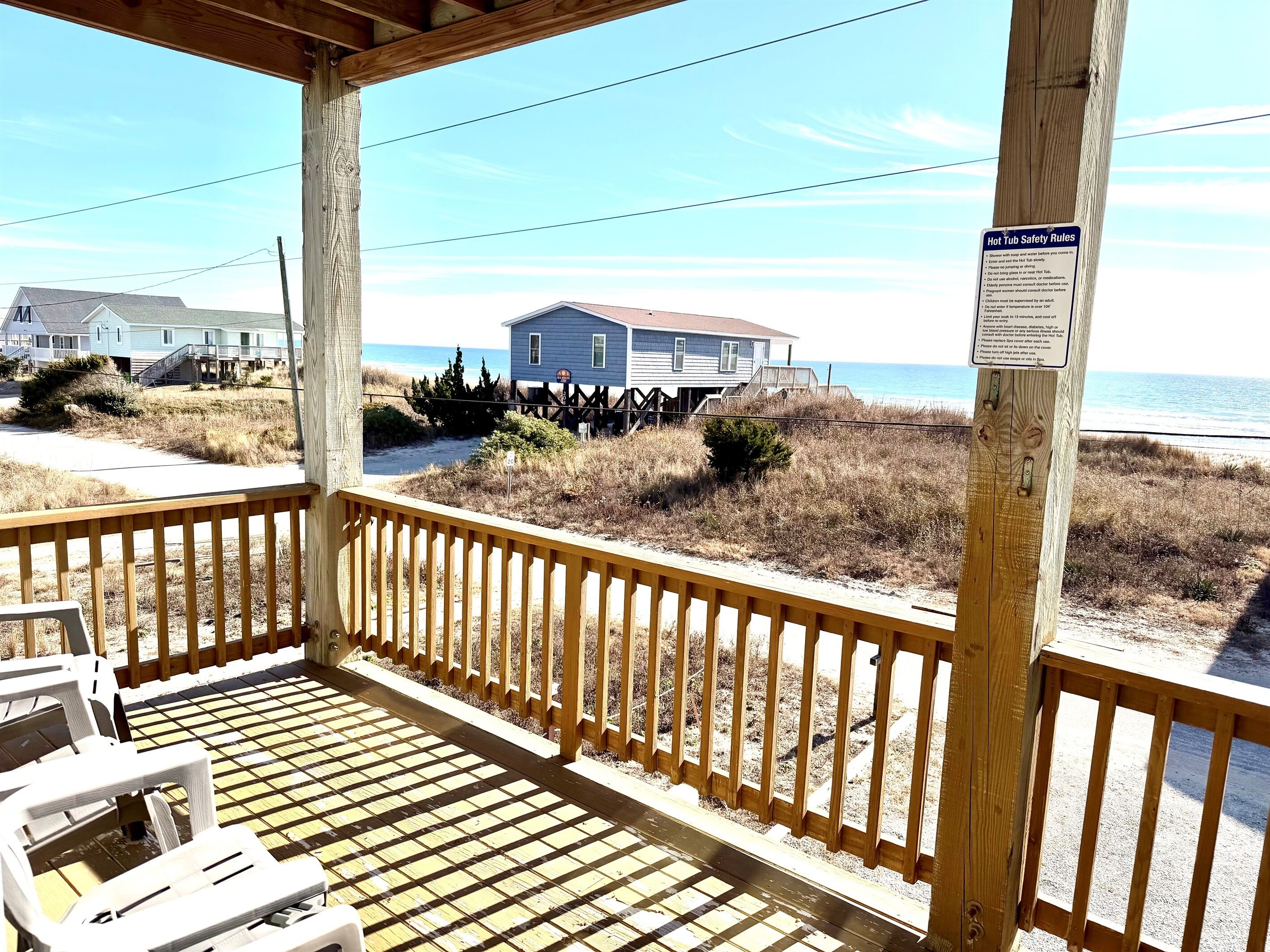 A wooden deck with a view of the beach and a house.