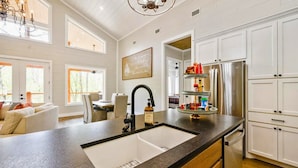 A modern kitchen with a large island, white cabinetry, and a chandelier.