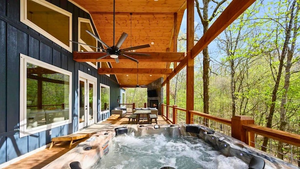 A hot tub in a covered outdoor area with wooden beams and a view of trees.