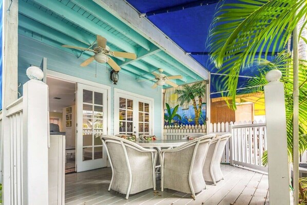 A covered outdoor patio with a table and chairs, ceiling fans, and a mural on the wall.