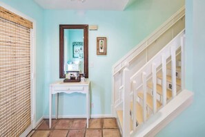 Un couloir avec une console blanche, un miroir et un tableau encadré accroché au mur.