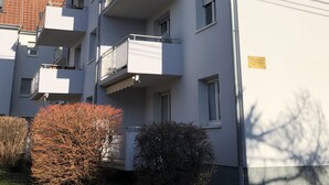 Ein mehrstöckiges Wohngebäude mit Balkonen und blauem Himmel.
