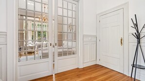 Ein Zimmer mit Holzboden, weißen Türen und einer schwarzen Stehlampe.