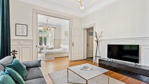 Ein Wohnzimmer mit grauem Sofa, Couchtisch, Flachbildfernseher und Kamin.