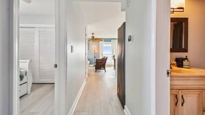 A hallway with a wooden floor, a dining area with a table and chairs, and a kitchen area with cabinets and a sink. - 3Bedroom Beachfront Condo-Gulf View-On the Sand! (Indian Rocks Beach)