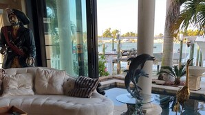 A luxurious living room with a plush sofa, a decorative statue, and a view of a marina.