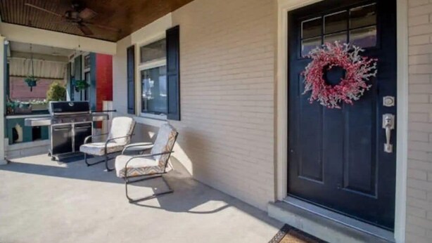 Una zona patio coperta con una porta nera, pareti bianche e una ghirlanda sulla porta.