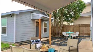 A backyard patio with outdoor furniture, a 'HOME' sign, and a wooden fence. - Staycation House | Modern and Spacious (Austin)