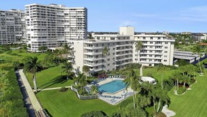 Ett hotell med flera våningar, en swimmingpool och välskötta trädgårdar.