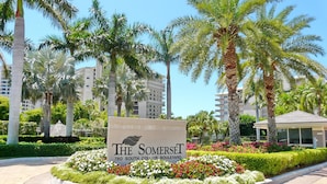 A sign for The Somerset at 780 South Collier Boulevard, surrounded by well-maintained landscaping and palm trees. - Beachfront Condo With Pools, Tennis Courts and gym (Marco Island)