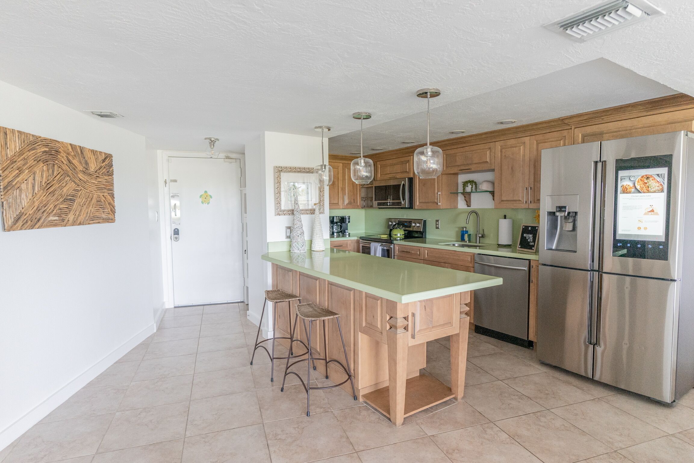 A modern kitchen with a central island, stainless steel appliances, and pendant lighting.