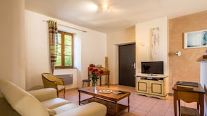 Un salon comprenant un canapé, une table basse, un meuble pour la télévision et une porte.