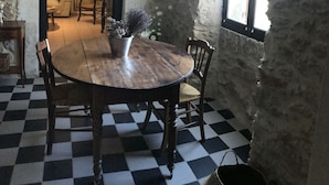Un coin repas avec un sol à carreaux, une table ronde en bois et quatre chaises.