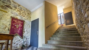 Un escalier en pierre mène à une pièce dont le sol est recouvert de carreaux et qui contient une table en bois.