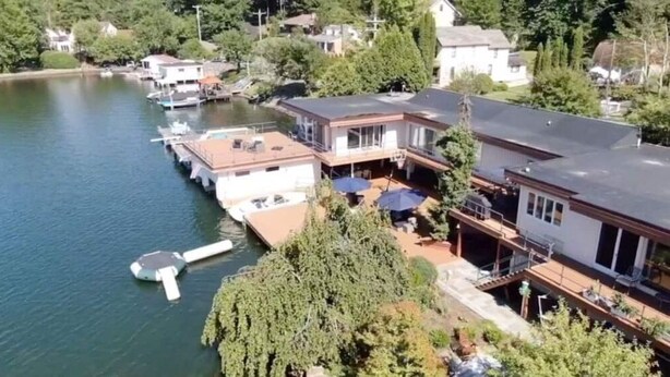 A lakeside property with a dock, a boat, and a house with a balcony overlooking the water.