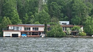 A lakeside property with a main building and a smaller structure, surrounded by dense forest.