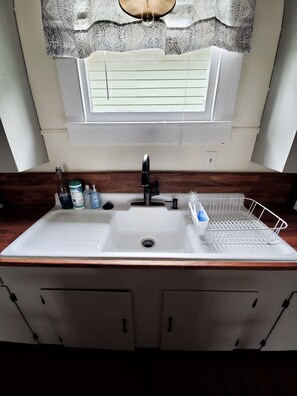 A bathroom with a white sink, a window above the sink, and a mirror. - Cozy Bungalow located 2 blocks from the beach-  (Galveston)