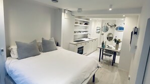 A modern bedroom with a large bed, built-in wardrobe, and a small dining area.
