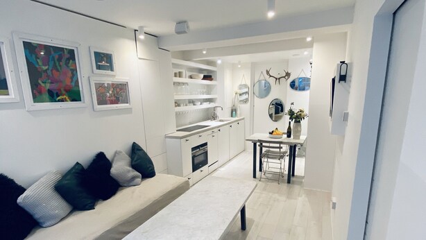 A modern living room with a sofa, a coffee table, and a dining area with a table and chairs.