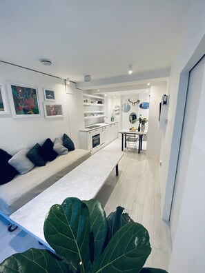 A modern living room with a sofa, a coffee table, and a dining area with a table and chairs.