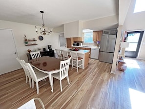Un'ampia cucina con zona pranzo, pavimento in legno e lampadario.