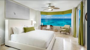 Een slaapkamer met een groot bed, een bureau, een stoel en uitzicht op de oceaan door een raam.