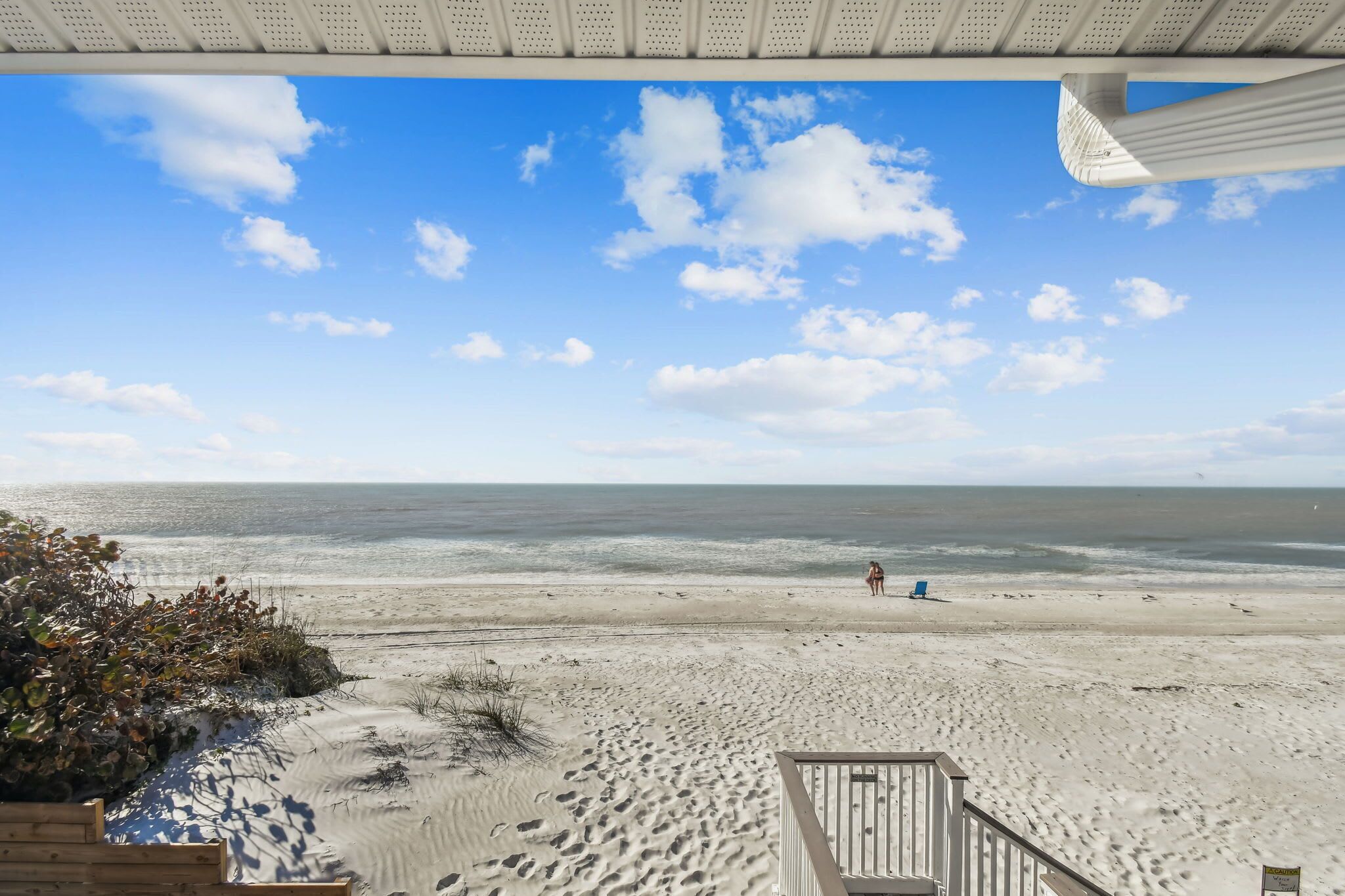 A beach view with a wooden deck and a railing.