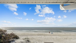 A beach view with a wooden deck and a railing.