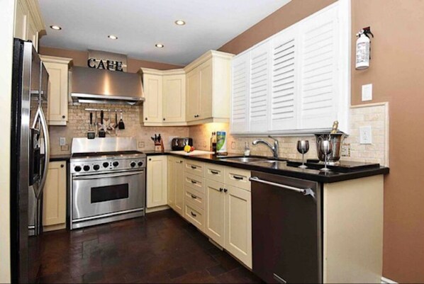 Kitchen features a central island, stainless steel range hood, oven, refrigerator, and dishwasher.