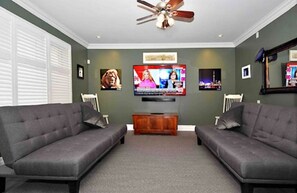 Relax in this stylish living room with two sofas, a flat-screen TV, and a ceiling fan.