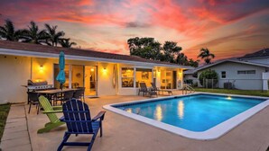 A backyard with a swimming pool, outdoor furniture, and a barbecue area. - Wildlife Views at CocoaBeachRetreat WaterfrontOasis,PrivatePool&WildlifeOnCanal! (Cocoa Beach)