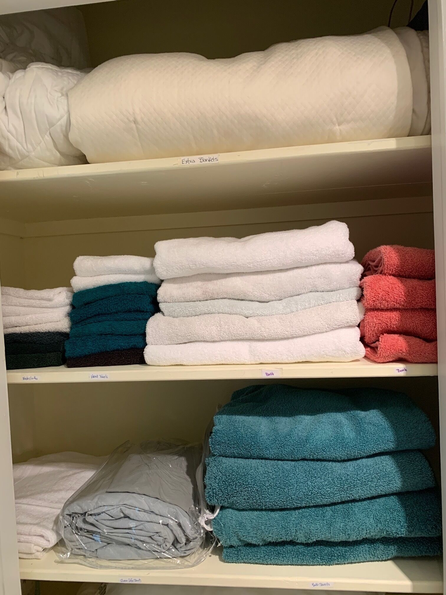 Une étagère de rangement avec des serviettes pliées de différentes couleurs.
