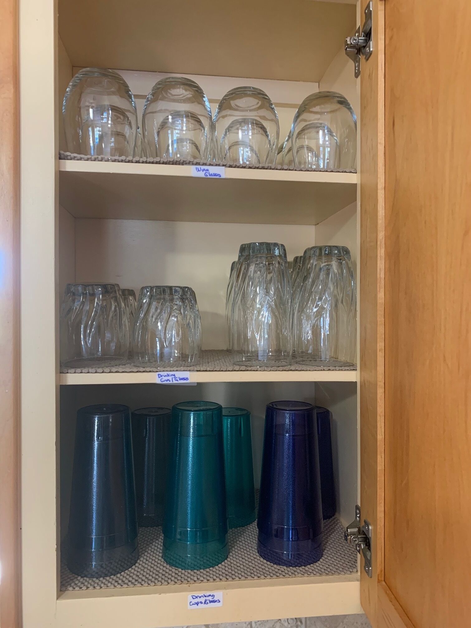 Un armario con estantes que contiene copas de vino, vasos y vasos tipo tumbler.