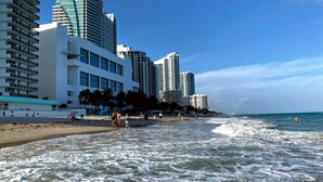 Ein Hotel direkt am Strand mit mehreren Hochhäusern, einem Sandstrand und Wellen.