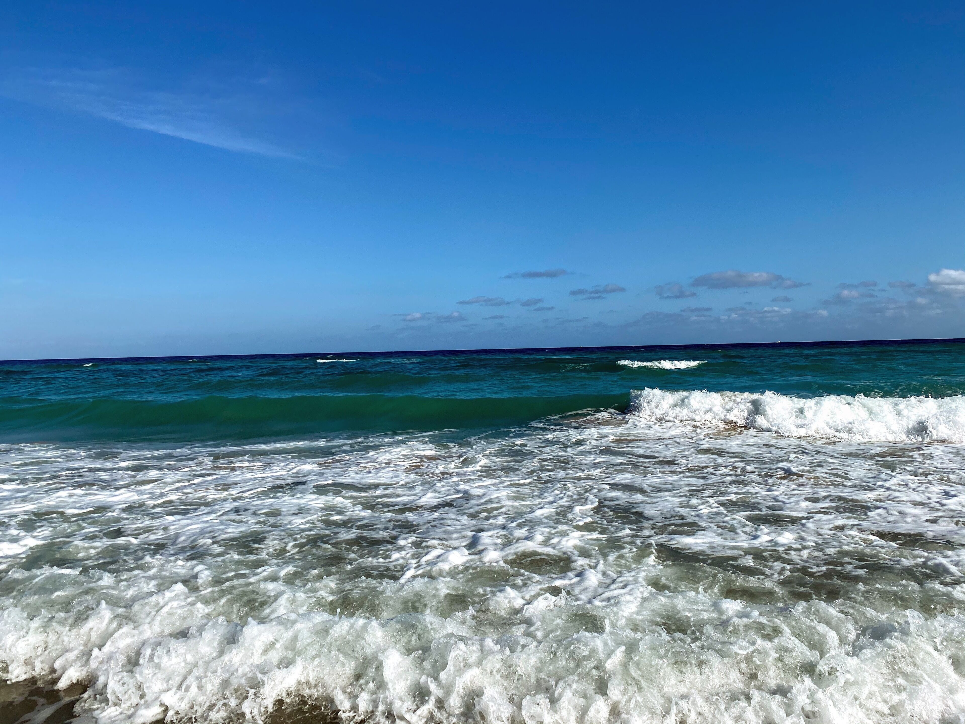 Ein Strand mit klarem, blauem Wasser und Wellen.