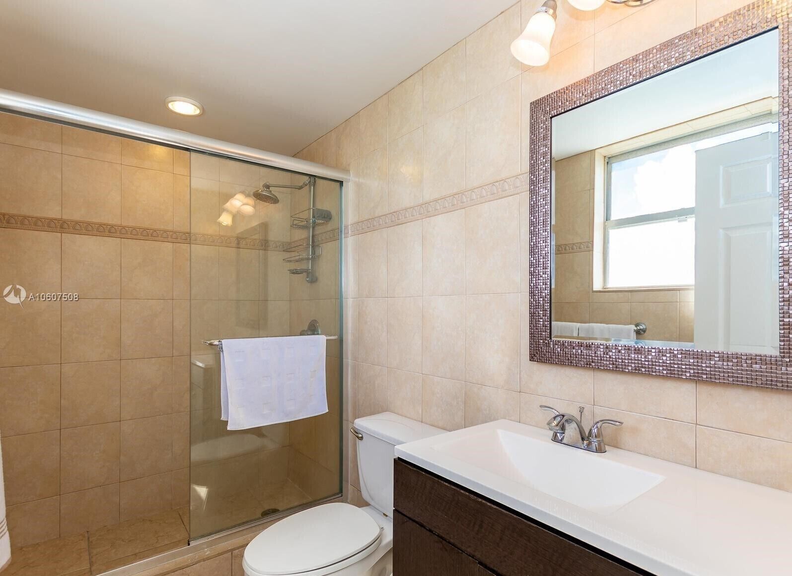 A modern bathroom with a glass shower enclosure, a white toilet, and a vanity with a mirror.