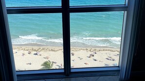 Blick auf einen Strand durch ein Fenster mit gefliestem Boden.