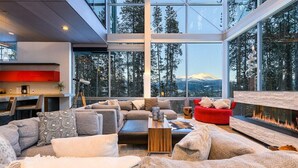 Un salon moderne doté d’une grande fenêtre, d’une cheminée et offrant une vue sur une montagne.