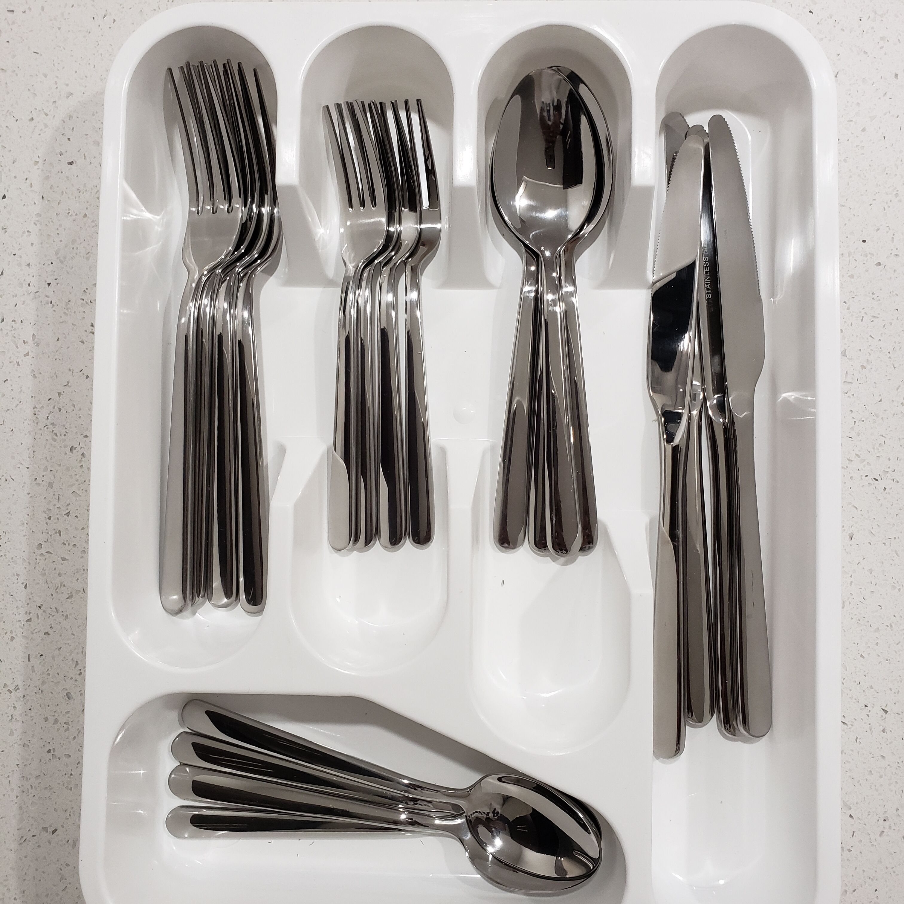 Un plateau blanc avec cinq fourchettes, une cuillère et un couteau.