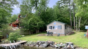Une cabane avec une terrasse, une table de pique-nique et une petite piscine.