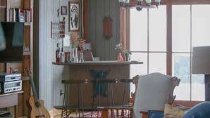 Un intérieur rustique avec un plafond en bois, un coin bar, une guitare et un fauteuil bleu.