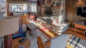 Un intérieur chaleureux avec une cheminée en pierre, des meubles en bois et un téléviseur.