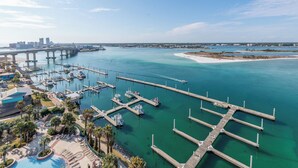 Une vue aérienne d’une marina avec de nombreux quais, une piscine et un pont en arrière-plan.