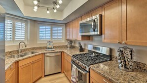 A modern kitchen with wooden cabinets, granite countertops, stainless steel appliances, and a skylight. - Central Tucson Gated Retreat (Tucson)