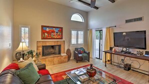 A living room with a fireplace, a television, and a ceiling fan. - Central Tucson Gated Retreat (Tucson)