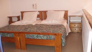 A bedroom with a wooden bed, a nightstand, and a dresser. - Androulakis Apartments (Platanias)