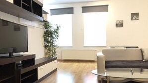 A modern living room with a flat-screen TV, a glass coffee table, a sofa, and a potted plant. - Wildbach City Apartments (Zell am See)